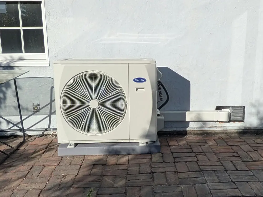 A Carrier ductless outdoor unit installed on a brick patio.